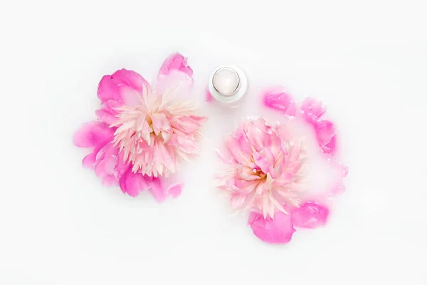 Cream and peony flower in a bath with milk. Conceptual photo: the best cosmetic tool for body and face care. Gentle care. Natural cosmetics.