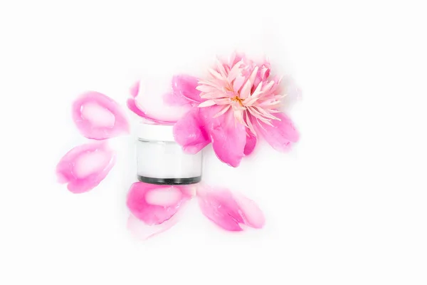 Cream and peony flower in a bath with milk. Conceptual photo: the best cosmetic tool for body and face care. Gentle care. Natural cosmetic product, mockup.