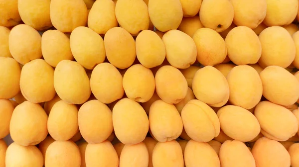Apricot background for beautiful wallpaper. Yellow apricots for fruit background with copy space. Abundance of apricots nicely laid out on the market counter.