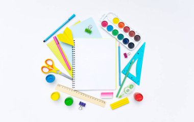 Çok renkli ofis kırtasiyesi ve aksesuarlarının arka planına karşı bir yay üzerine okul defteri. .