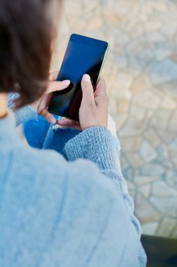 Akıllı telefondan konuşan ve akıllı telefonla mesajlar yazan genç bir kız.