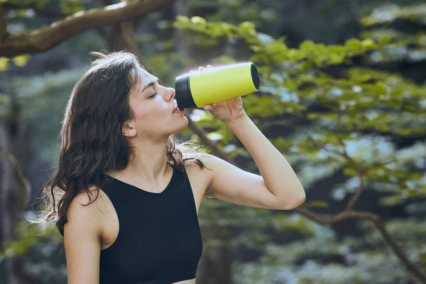 Gesundes Fitness-Girl trinkt Wasser aus grüner Flasche im Wald — Stockfoto