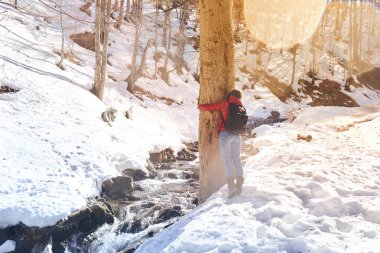 Genç kız, kış parkında bir ağaç gövdesine sarıldı.