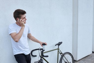 Şehirde bisiklet ile poz yakışıklı hipster adam.