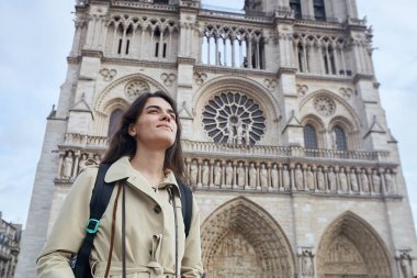 Paris 'teki ünlü Notre Dame katedralinin önünde gülümseyen genç bir turist.