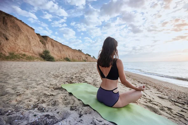 Boldog fiatal nő gyakorlatok jóga és meditál a lótusz helyzet a strandon — Stock Fotó