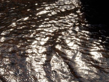 Dalgalar ve güneş tarafından aydınlatılmış su yüzeyinde ripples