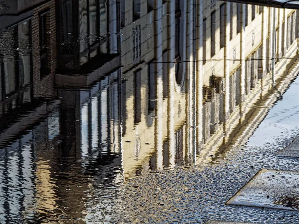 Reflection in a puddle on the street of a residential building on a Sunny day