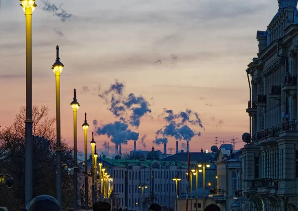 Evening street with old houses against the background of Smoking chimneys at winter