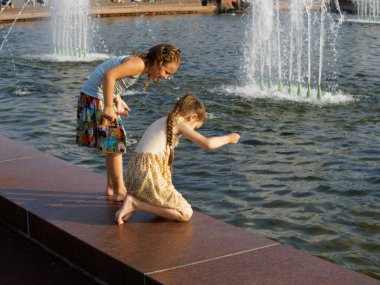 Moskova, Rusya, 30 Temmuz 2016: Bir tanesi elinde olta tutan iki kız, Par 'daki havuzda bir şeye bakıyor