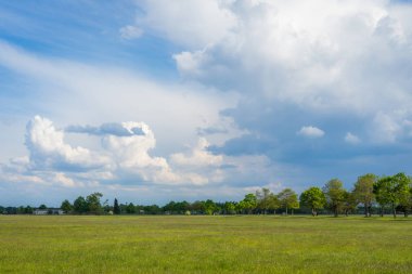 landscape photo of a green field with cloudy sky