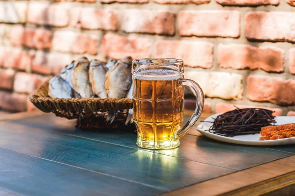 Tazza con birra e snack su uno sfondo di un muro di mattoni sul tavolo. Il concetto di relax, bar e feste — Foto Stock