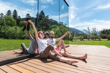 Maskeli genç çift yazın dağdaki bir evin terasında dinleniyor. 2020 'de dinlenme ve tatil kavramı