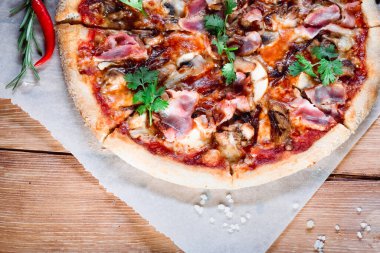 Otlar ve baharatlarla çevrili ahşap bir masada iştah açıcı pizza. Lezzetli yemekler, restoranlar ve kafeler.