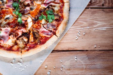 Otlar ve baharatlarla çevrili ahşap bir masada iştah açıcı pizza. Lezzetli yemekler, restoranlar ve kafeler.