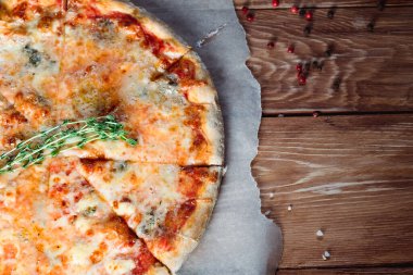 Otlar ve baharatlarla çevrili ahşap bir masada iştah açıcı pizza. Lezzetli yemekler, restoranlar ve kafeler.