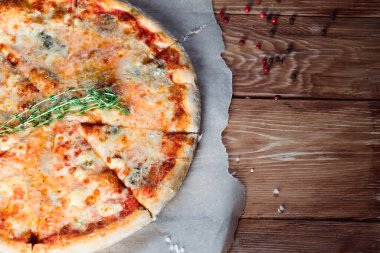 Otlar ve baharatlarla çevrili ahşap bir masada iştah açıcı pizza. Lezzetli yemekler, restoranlar ve kafeler.