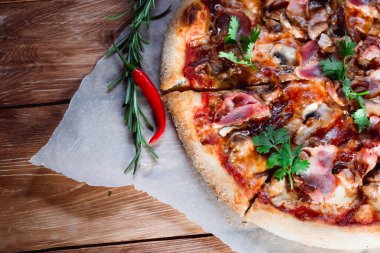 Otlar ve baharatlarla çevrili ahşap bir masada iştah açıcı pizza. Lezzetli yemekler, restoranlar ve kafeler.