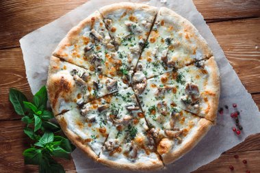 Otlar ve baharatlarla çevrili ahşap bir masada iştah açıcı pizza. Lezzetli yemekler, restoranlar ve kafeler.