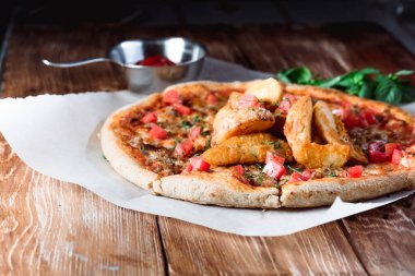 Otlar ve baharatlarla çevrili ahşap bir masada iştah açıcı pizza. Lezzetli yemekler, restoranlar ve kafeler.