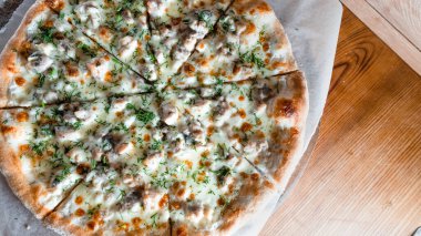 Otlar ve baharatlarla çevrili ahşap bir masada iştah açıcı pizza. Lezzetli yemekler, restoranlar ve kafeler.