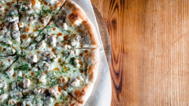 Otlar ve baharatlarla çevrili ahşap bir masada iştah açıcı pizza. Lezzetli yemekler, restoranlar ve kafeler.