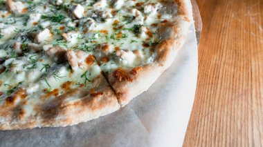 Otlar ve baharatlarla çevrili ahşap bir masada iştah açıcı pizza. Lezzetli yemekler, restoranlar ve kafeler.