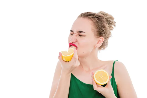 Retrato emocional de uma linda garota em um fundo branco isolado que está comendo um limão. O conceito de uma dieta saudável, estilo de vida saudável e vegetarianismo — Fotografia de Stock