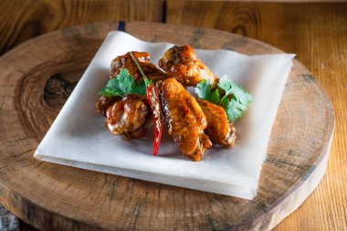 Ahşap tepside soslu tavuk kanadı. Yemek ve servis kavramı, barlarda ve restoranlarda yemek.