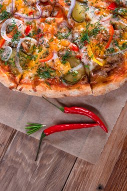 Otlar ve baharatlarla çevrili ahşap bir masada iştah açıcı pizza. Lezzetli yemekler, restoranlar ve kafeler.