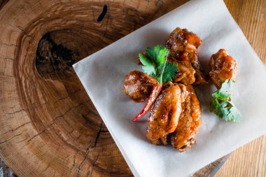 Ahşap tepside soslu tavuk kanadı. Yemek ve servis kavramı, barlarda ve restoranlarda yemek.