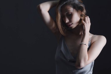 Gri ipek elbiseli, siyah arka planda güzel bir genç kızın portresi. Güzellik, gençlik ve doğallık kavramı