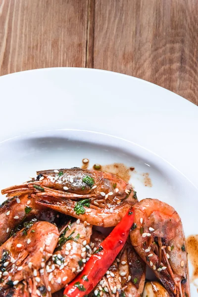 Camarones fritos apetitosos con especialidades, semillas de sésamo y limón, en un plato blanco sobre un fondo de madera. Concepto de comida en restaurantes y bares — Foto de Stock