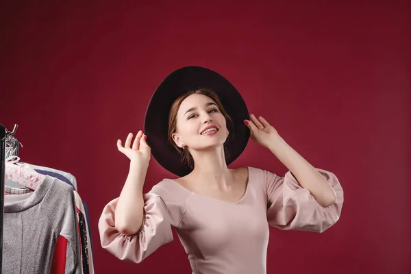 Retrato de uma menina bonita em um vestido rosa e chapéu em um fundo vermelho no estúdio. Vestuário, montagem e conceito de beleza — Fotografia de Stock