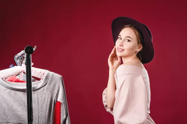 Retrato de uma menina bonita em um vestido rosa e chapéu em um fundo vermelho no estúdio. Vestuário, montagem e conceito de beleza — Fotografia de Stock