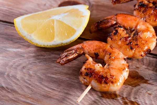 Appetizing fried shrimp on a skewer on a wooden surface among lemon and seasonings. The concept of fast and wholesome food — Stock Photo, Image