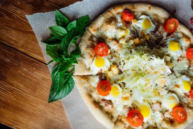 Otlar ve baharatlarla çevrili ahşap bir masada iştah açıcı pizza. Lezzetli yemekler, restoranlar ve kafeler.