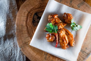 Ahşap tepside soslu tavuk kanadı. Yemek ve servis kavramı, barlarda ve restoranlarda yemek.