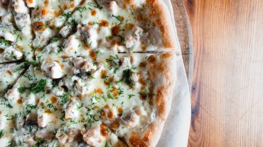 Otlar ve baharatlarla çevrili ahşap bir masada iştah açıcı pizza. Lezzetli yemekler, restoranlar ve kafeler.