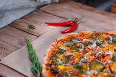 Otlar ve baharatlarla çevrili ahşap bir masada iştah açıcı pizza. Lezzetli yemekler, restoranlar ve kafeler.