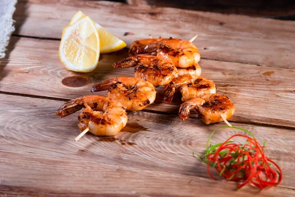 Appetizing fried shrimp on a skewer on a wooden surface among lemon and seasonings. The concept of fast and wholesome food — Stock Photo, Image