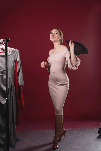 Retrato de uma mulher bonita em um vestido rosa e chapéu em um fundo vermelho no estúdio. Vestuário, montagem e conceito de beleza — Fotografia de Stock