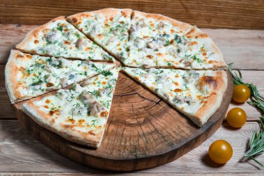 Otlar ve baharatlarla çevrili ahşap bir masada iştah açıcı pizza. Lezzetli yemekler, restoranlar ve kafeler.