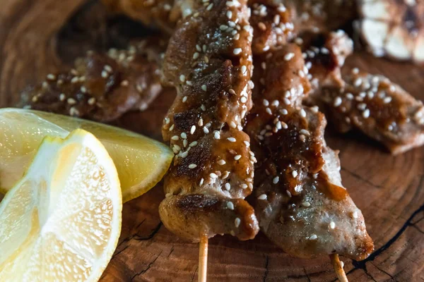 Los pedazos apetitosos de la carne en las brochetas sobre el fondo de madera. Concepto de comida y servicio — Foto de Stock