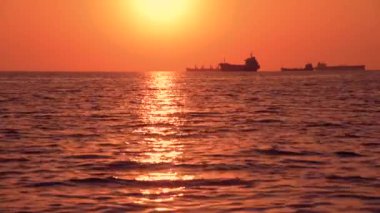 Denizde güzel bir gün batımı. Dalgaların ve teknelerin manzarası. Eğlence ve eğlence anlayışı.