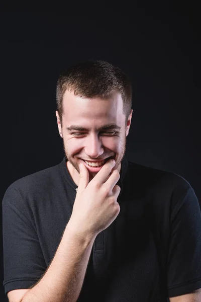 Retrato de um jovem bonito emocional, em um fundo preto no estúdio, que está gesticulando. Expressão de emoções e sentimentos — Fotografia de Stock