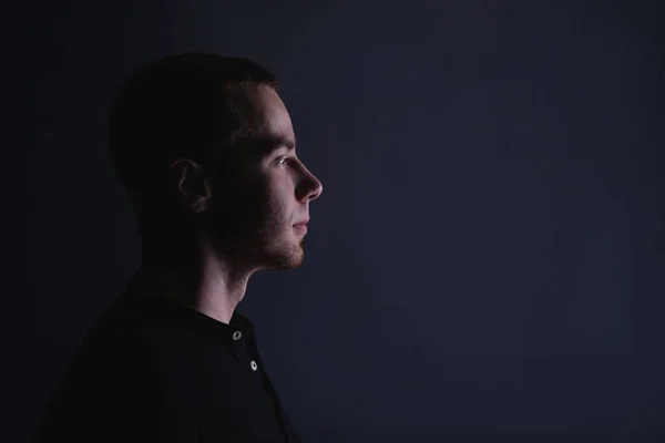 Portrait of an emotional handsome young man, on a black background in the studio, who stands in a brooding pose. Expression of emotions and feelings — Stock Photo, Image