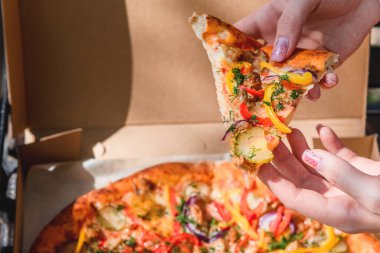 Güzel, genç bir kadın sokakta pizza ve patates kızartması yiyor. Fast food, yemek teslimatı ve doğada öğle yemeği kavramı.