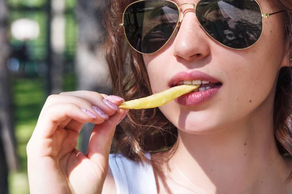 Uma jovem linda a comer pizza e batatas fritas na rua. O conceito de fast food, entrega de alimentos e almoço na natureza — Fotografia de Stock