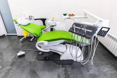 Diş sağlığı kliniğinde yeşil dişçi koltuğu ve tıbbi ekipman. Tıp kurumlarında sağlık ve tedavi kavramı